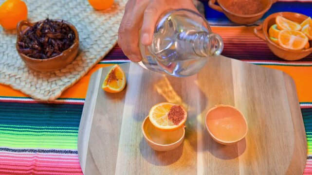 Serving traditional mexican mezcal with chapulines and orange