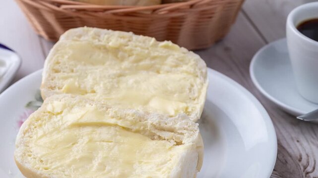 French bread or salt bread with butter and coffee over white wooden table
