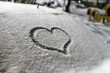 Valentine's Day concept: hand-drawn heart pattern on a frozen car windshield. Hand drawn heart shape on windshield of the car. Love symbol. Romantic background. A frozen windshield with a heart. 