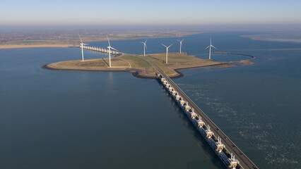 Aerial view of the Neeltje Jans artificial island with wind turbines and the Oosterscheldekering barrier cutting through the serene waters, Vrouwenpolder, Zeeland, Netherlands.