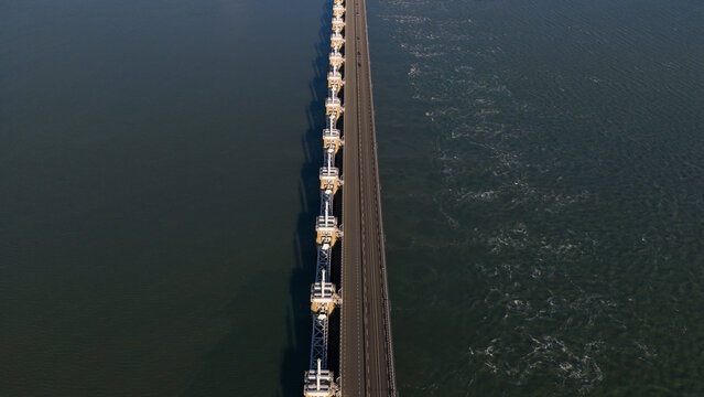 Aerial view of the Oosterscheldekering barrier slices through the water, the concrete pillars casting long shadows in the winter sun, Vrouwenpolder, Zeeland, Netherlands.