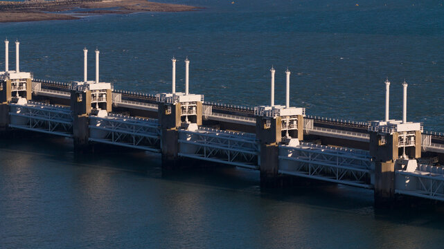 Aerial view of the magnificent Oosterscheldekering barrier slicing through the tranquil, deep blue waters, a testament to human engineering, Vrouwenpolder, Zeeland, Netherlands.
