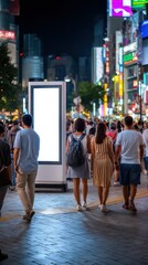 Obraz premium People Walking Past Blank Vertical Billboard in Busy City at Night