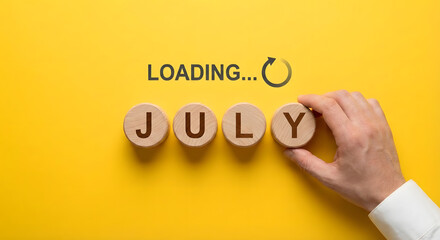 July month loading concept with wooden blocks and hand