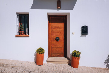 Typical Spanish town street. Whitewashed house with wooden door and two potted plants flank the entrance