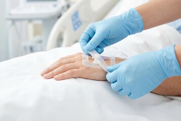 Patient receives wound care in a hospital setting while a healthcare worker applies a dressing to the hand in the afternoon