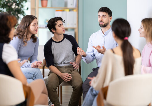 Students are sitting in circle, talking. Lecture room is filled with listeners. Company managers during training, introductory training for staff, professional development courses, educational seminar - Powered by Adobe