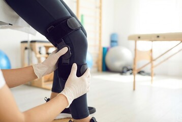 Knee support being fitted on a person in a rehabilitation center during a therapy session for injury recovery