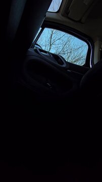 Vertical interior view of a young blonde woman entering a car and sitting in the passenger seat. Urban travel and commuting video.