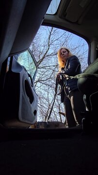 Dog running out of car door opened by woman. Interior view from vehicle cabin. Urban pet lifestyle video. Shot from inside parked car, woman opens door, eager dog leaps out onto city street or park