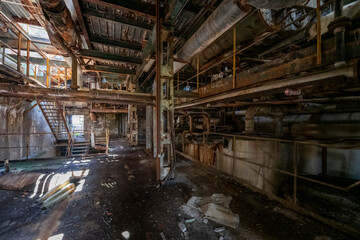 Fototapeta premium Derelict industrial hall of an abandoned Italian sugar mill. Large warehouse ruins with decaying walls and urban exploration atmosphere