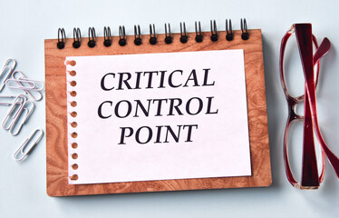 CRITICAL CONTROL POINT - words on a white sheet of paper on the background of a notebook, glasses...