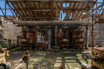 Derelict industrial hall of an abandoned Italian sugar mill. Large warehouse ruins with decaying walls and urban exploration atmosphere