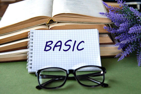 Notebook with BASIC text on a green background with books and glasses