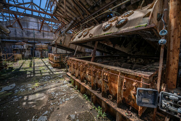 Fototapeta premium Vintage machinery inside an abandoned sugar refinery in Italy. Rusted equipment and industrial decay in a defunct factory hall
