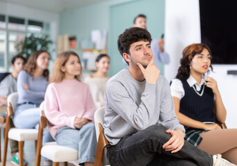 Obraz premium Group of young people attend classes to prepare for exams, they participate in lectures and discussions. Students carefully watch the presentation