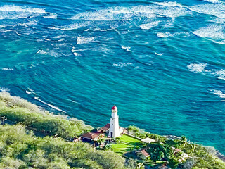 Aerial view of the Diamond Head Lighthouse standing proudly against the turquoise ocean, its red cap a beacon of hope, Honolulu, Hawaii, United States.
