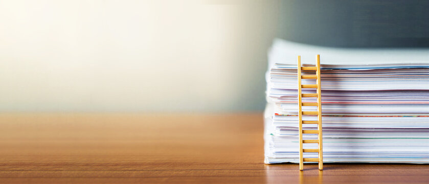 Stack of documents with small wooden ladder on desk, career growth, bureaucracy pressure, corporate ladder, office life, paperwork overload, productivity stress, administrative burden