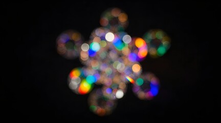 Abstract out-of-focus display of colorful lights creates a snowflake-like pattern on a black background