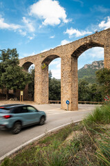 Road trip on Mallorca, a car drives past old aqueduct