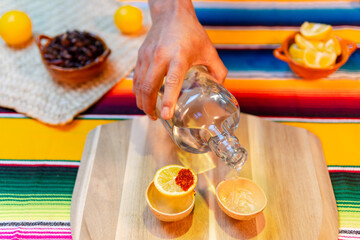 Hand pouring mezcal into traditional jicara cups