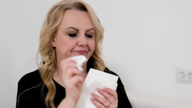 Woman blowing nose Woman blowing her nose in the room Woman, tissue and blowing nose. Female person, sick and sofa in home for bacteria problem in lounge with fatigue, sinus or influenza