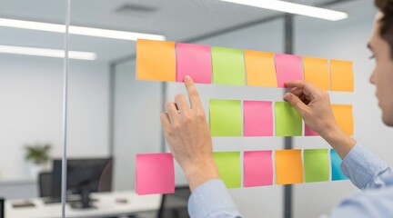 Man attaching colorful sticky notes to a glass wall in the office