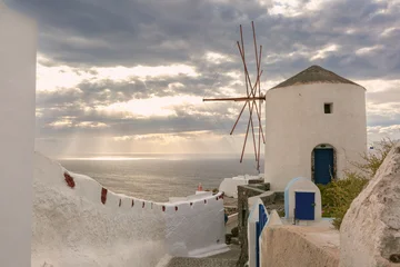 Selbstklebende Fototapeten Santorini Historic white windmill overlooking the Aegean Sea in Oia village on Santorini island, Greece at sunset.  © Kavalenkava