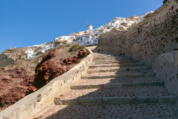 Stone stairway leading up to white Cycladic houses and windmill in Oia village on Santorini island, Greece.