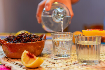 Pouring mezcal drink with chapulines and orange slice
