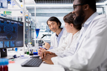 Multiethnic lab researchers team evaluating genetic markers associated with disease risk on PC. Multiracial laboratory engineers study DNA strand mapping with genomics analysis program on computer