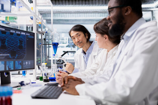 Multiethnic lab researchers team evaluating genetic markers associated with disease risk on PC. Multiracial laboratory engineers study DNA strand mapping with genomics analysis program on computer - Powered by Adobe