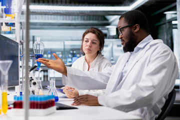 Team of lab scientists working together on PC, evaluating genetic markers associated with disease risk. Teamworking colleagues study DNA strand mapping with genomics analysis program on computer