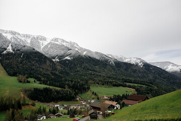 Alpine village nestled in a valley with snow-capped mountains and evergreen forests