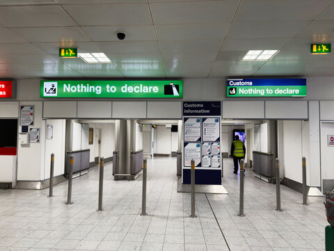 Customs hall in Manchester airport with Nothing to declare green signs and security checkpoint