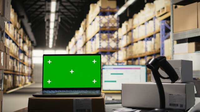 Empty distribution warehouse with mockup display on laptop used for large business retail operations, industrial space with racks and shelves for goods storage. Fulfillment center e-commerce.