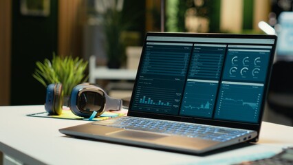 Modern laptop showcasing data reports in an empty office late at night, performance metrics and...