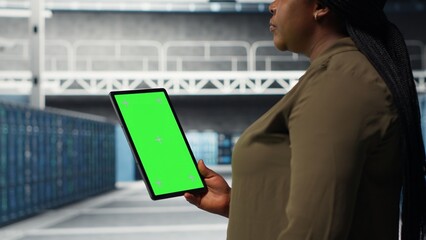 Developer in data center using isolated screen tablet to upgrade systems for increased stability. IT expert in server farm configuring hardware with chroma key device for optimum performance, camera B