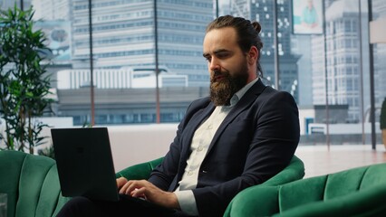 Confident businessman manages corporate expenses on laptop, determined professional in a corporate office reviews financial reports. Ensures a successful career and leadership skills. Camera B.