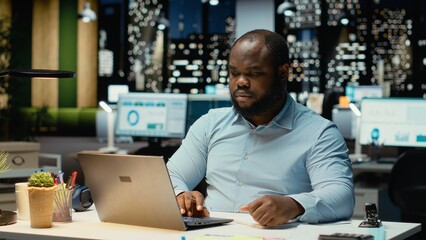 Black office employee ripping a piece of paper after making a mistake, restarting his task in anger...