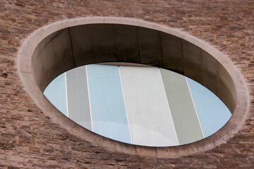Beautiful round window made of pieces of glass of different colors against a brick wall on a cloudy winter day.