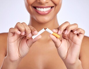 Close-up of a smiling person holding a broken cigarette in both hands, symbolizing quitting smoking, promoting a healthy lifestyle, and taking a stand against tobacco use.