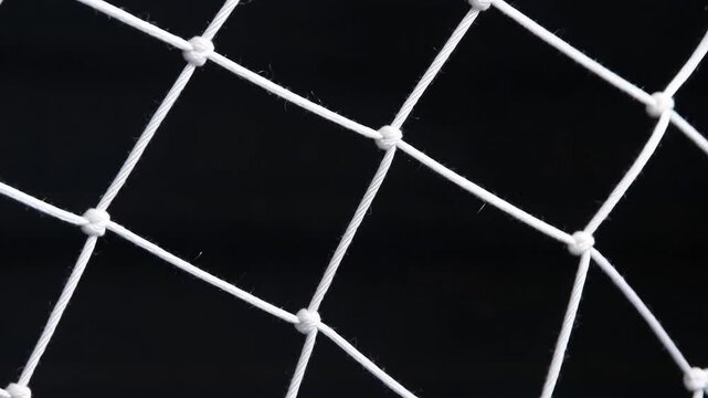 White rope soccer goal net with knots in closeup on solid black background