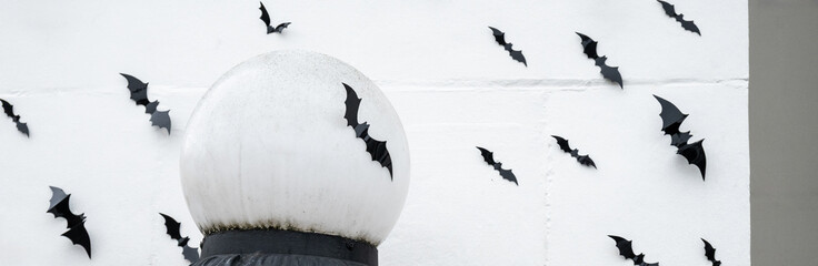 Scary and creepy Halloween background, exterior of white building decorated with a cauldron of plastic bats flying across the scene

