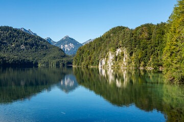 Calm Alpsee Lake With Mountain Reflections And Green Forest in Schwangau, Germany