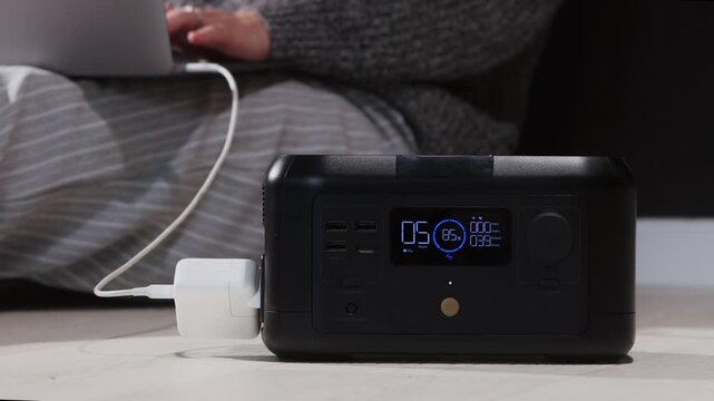 A person uses a laptop connected to a portable power station for charging, highlighting remote work convenience and off-grid power solutions
