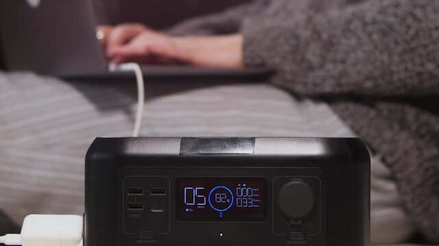 A person is working on a laptop connected to a portable power station, indicating remote work convenience and off-grid power solutions