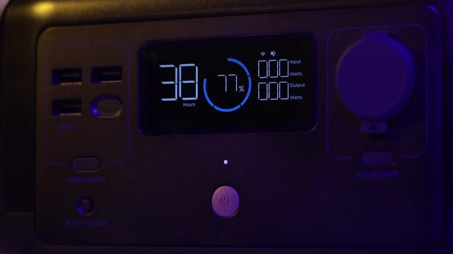 Close-up of a portable power station's digital screen displaying remaining hours, battery percentage, and power input/output watts