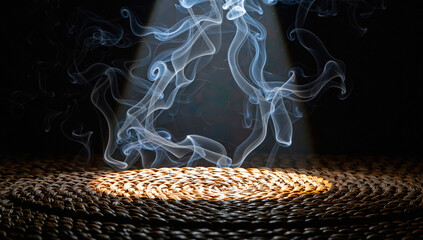 A dramatic scene of smoke rising from a lit surface in a dark room with a spotlight