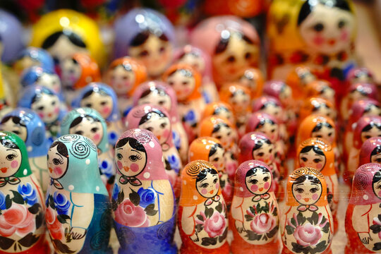 Large group of colorful wooden russian matryoshka nesting dolls standing in rows on souvenir shop shelf